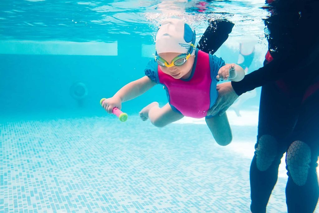 Dziecko nurkujące w basenie pod okiem instruktora